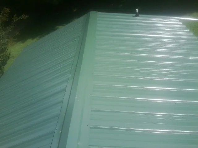 New green metal panels meeting at the ridge of a roof — Flat Roof Repair work by our crew in Dale