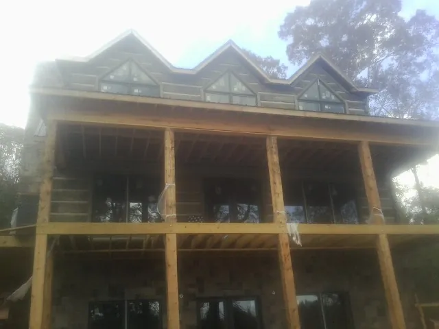 Dormers and porch framing on a large log home under construction — Roof Coating work by our crew in Dale