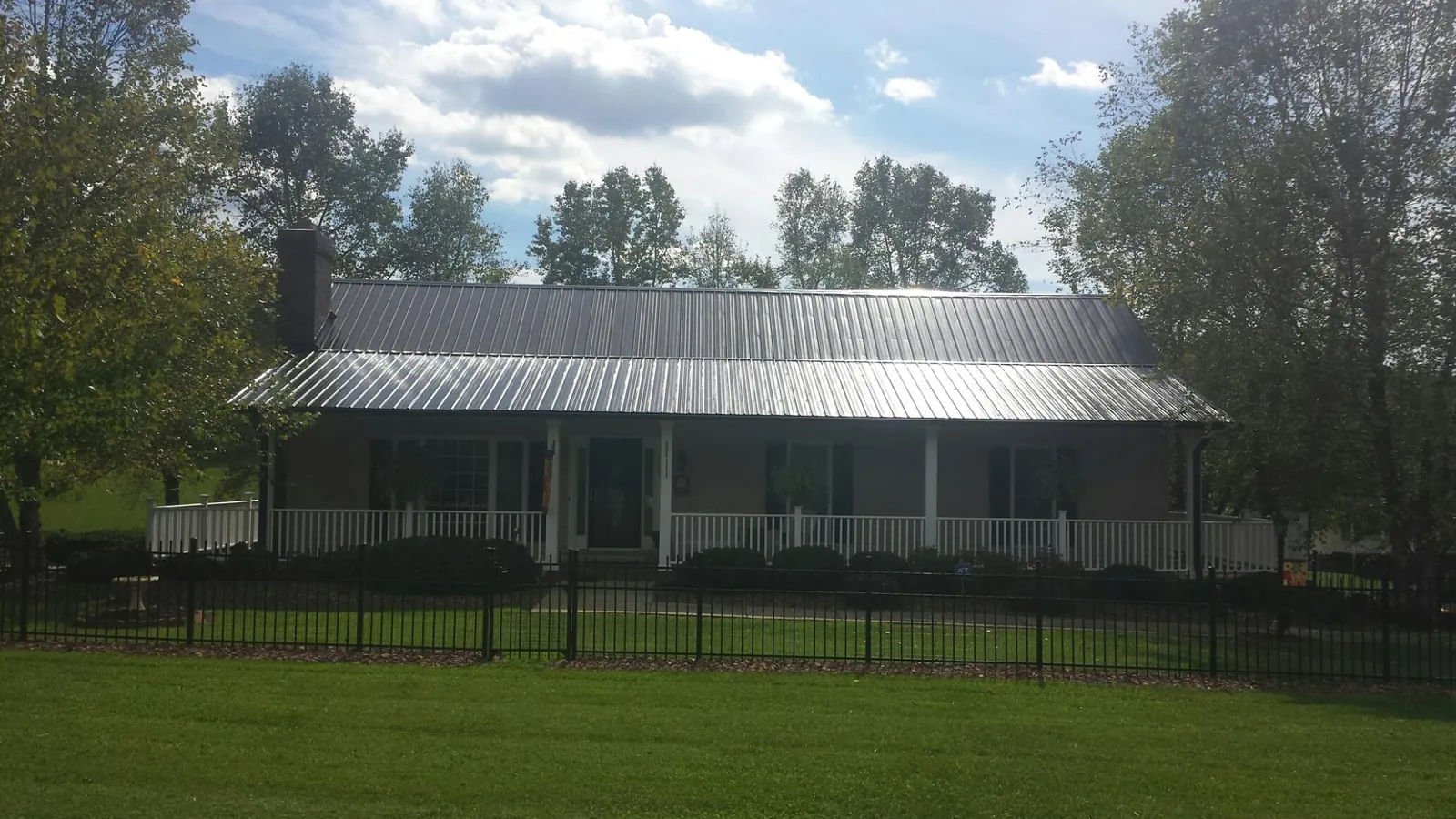 Gray metal roof on a brick ranch with a full width front porch — Gutter Guard Installation work by our crew in Dale